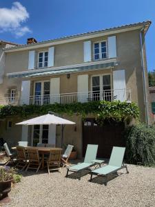 a house with chairs and a table and an umbrella at Le Caprice garden, river and chateau in Saint-Germain-de-Confolens