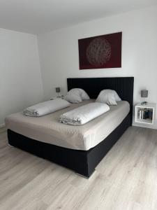 a large bed in a bedroom with a black frame at Helle Ferienwohnung Waldblick mit Balkon und Garten in Hatten
