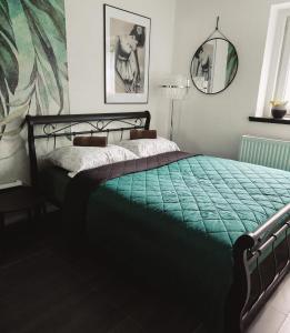 a bedroom with a bed with a green comforter at Oaza Spokoju in Szczawno-Zdrój
