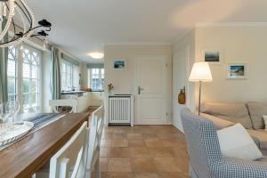 Una cocina y una sala de estar con mesa y sillas. en Haus Landleben, en Borgsum