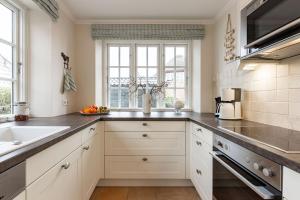 Una cocina con gabinetes blancos y un fregadero. en Haus Landleben, en Borgsum