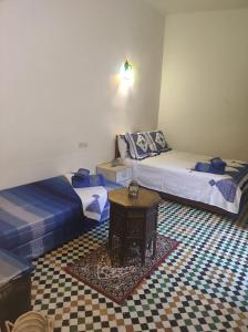 two twin beds in a room with a table at Riad Bennouna in Fez