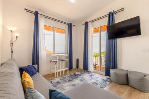 a living room with a couch and a tv at Coastal São Vicente Mountain & Sea View Hideaway with Free Parking in São Vicente