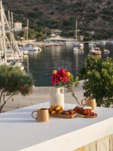 a table with a plate of food and a vase with flowers at Alýria Sea Side Suites in Agios Nikolaos