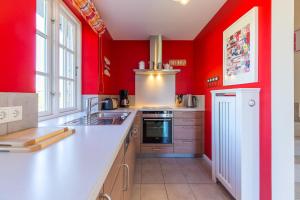 a kitchen with red walls and a white counter top at Haus Marie in Utersum