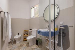 a bathroom with a toilet and a sink and a mirror at Coastal São Vicente Mountain & Sea View Hideaway with Free Parking in São Vicente +39 photos