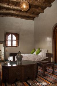 a bedroom with a bed with green pillows and a table at Tigmi Nomade in Tahannout