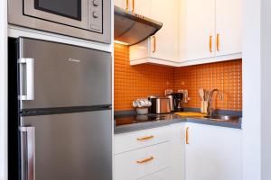 einen Kühlschrank aus Edelstahl in einer Küche mit weißen Schränken in der Unterkunft Home2Book Relaxing Coastal Studio in Adeje in Adeje