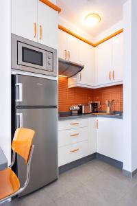 eine Küche mit weißen Schränken und einem Edelstahlkühlschrank in der Unterkunft Home2Book Relaxing Coastal Studio in Adeje in Adeje