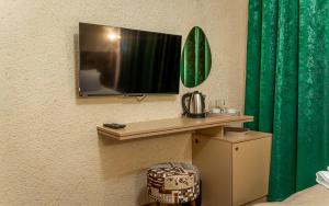 a tv on a wall with a green curtain at SION Boutique Guest rooms in Veliko Tŭrnovo