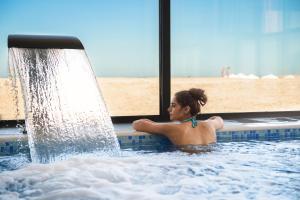 Eine Frau in einem Schwimmbad mit Wasserfall. in der Unterkunft Mirage Beach Spa Hotel in Eforie Nord + 90 Fotos
