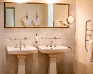 La salle de bains est pourvue de 2 lavabos, d'un miroir et de serviettes. dans l'établissement Auberge Ostapé, à Bidarray