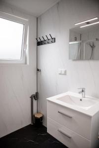a white bathroom with a sink and a window at Knus 3p-chalet met sauna in hartje Zeeland VP080 in Heinkensand