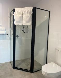 a bathroom with a shower and a toilet and towels at Distant Ocean View central bfast included in Charlestown