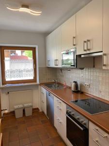 a kitchen with white cabinets and a sink and a window at Traumferienwohnungen Schliersee in Schliersee