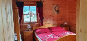 a bedroom with a bed with a red comforter and a window at Haus Walina in Tannheim +5 photos