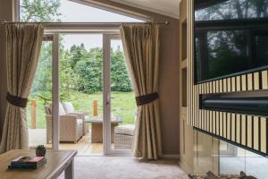 Una sala de estar con puertas corredizas de vidrio y vista al patio. en Jennywren Lodge, en Windermere