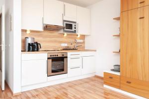 Una cocina con gabinetes blancos y un horno de estufa. en Haus Hanseatic, Wohnung 211, en Duhnen