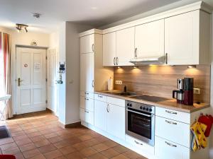 Una cocina con gabinetes blancos y una estufa. en Moin Moin, en Born 11 fotos más