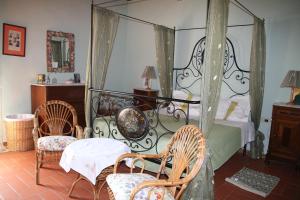 a bedroom with a canopy bed and two chairs at Il casale dei tigli in Limite