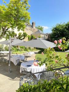 a group of tables and chairs under an umbrella at Hôtel 4 étoiles - Restaurants & Spa Périer Du Bignon in Laval