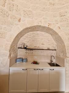 a kitchen with a stone wall and a sink at Stylish Trullo Pool Villa in Martina Franca