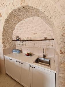 a kitchen with a sink and a stone wall at Stylish Trullo Pool Villa in Martina Franca