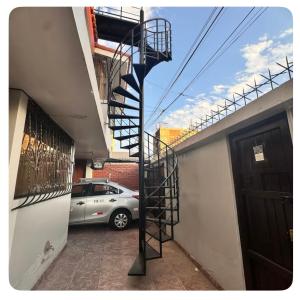 une voiture garée à côté d'un bâtiment avec un escalier en colimaçon dans l'établissement Habitación céntrica bonita vista, à Arequipa