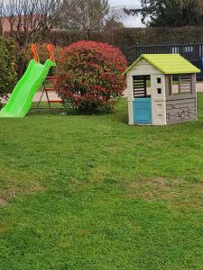 uno scivolo verde in un cortile accanto a una casetta da gioco di NOUVEAU - LE BOISSANTÉ - Zoo à 10 mn - Jeux pour enfants a Noyers-sur-Cher