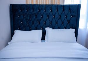 una cama con cabecera azul y almohadas blancas en Desired Atmosphere Safaris, en Nairobi 22 fotos más