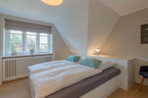a bedroom with a bed with white sheets and blue pillows at Hüs Holm in Alkersum