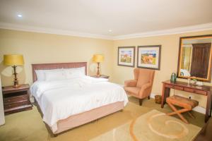 Un dormitorio con una cama grande y una silla. en The Presidential Mansion, en Durban