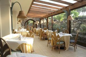 un ristorante con tavoli e sedie e un muro di pietra di Hotel dei Coralli a Marina di Campo