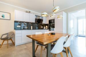 Una cocina con una mesa de madera y sillas blancas. en Quartier 7 App 03, en Ahlbeck 17 fotos más