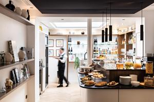 a chef standing in a kitchen with food on a counter at Best Western Premier The Blake Paris Gare Saint Lazare in Paris