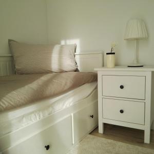 un lit avec une commode blanche et une lampe dans l'établissement Haus Luv & Haus Lee - Nordseebad Burhave, à Burhave 16 autres photos