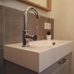 La salle de bains est pourvue d'un lavabo blanc et d'un robinet. dans l'établissement Haus Luv & Haus Lee - Nordseebad Burhave, à Burhave