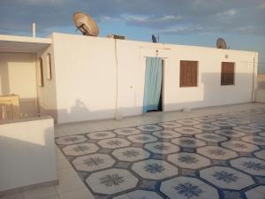 een wit gebouw met een blauwe deur en een tegelvloer bij Studio AMINE in Mahdia