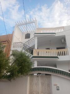 a white building with a balcony and stairs on it at Studio AMINE in Mahdia