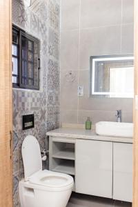 a bathroom with a white toilet and a sink at Katamba Apartments in Gwarinpa