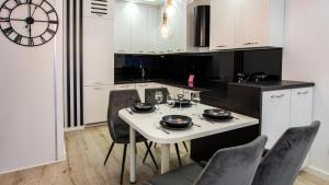 a kitchen with a table and chairs and a clock at VacationClub Let's Sea Baltic Park Apartament A20 in Gąski