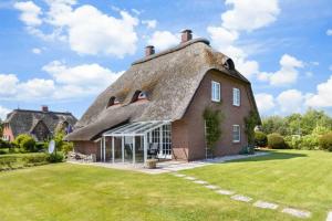 a thatch roofed house with a yard at Haushaelfte 16a Lille Hus ID 450 in Tating