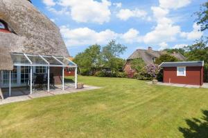 a house with a thatched roof and a yard at Haushaelfte 16a Lille Hus ID 450 in Tating