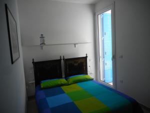 ポルト・チェザーレオにあるSule Mare Ientuのカラフルなベッドと窓が備わるベッドルーム1室が備わります。