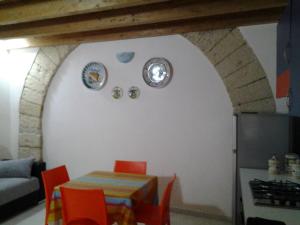 カステッランマーレ・デル・ゴルフォにあるLa marinaのキッチン(テーブル、オレンジの椅子、壁の皿付)