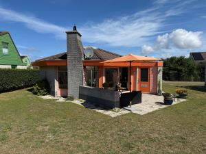 a house with an orange umbrella in the yard at Zeester 189 in Julianadorp