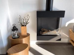 - un salon avec une cheminée et deux tabourets en bois dans l'établissement Ferienhaus Meerwunder, à Wangerland