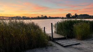 un pont en bois sur une étendue d'eau au coucher du soleil dans l'établissement Ferienhaus Meerwunder, à Wangerland 15 autres photos