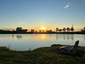 un banc assis sur l'herbe à côté d'un lac dans l'établissement Ferienhaus Meerwunder, à Wangerland