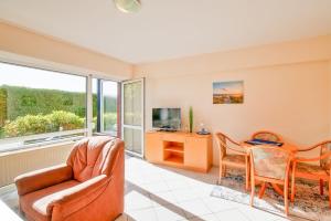 a living room with a chair and a table and a tv at Haus Seepferdchen in Schillig +19 photos